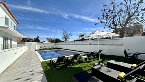 Ein Garten mit Swimmingpool, Gartenmöbeln und einem weißen Zaun.