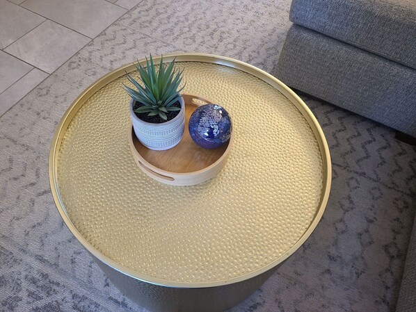 Une table ronde à la surface texturée, un pot contenant une plante succulente et un globe décoratif.
