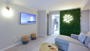 Uma sala de estar moderna com uma TV de tela plana, uma parede verde e um sofá cinza.