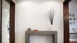 A modern interior with a concrete console table, a vase with branches, and a bowl. - Luxury Apartment with Exceptional View (Papagou-Holargos)