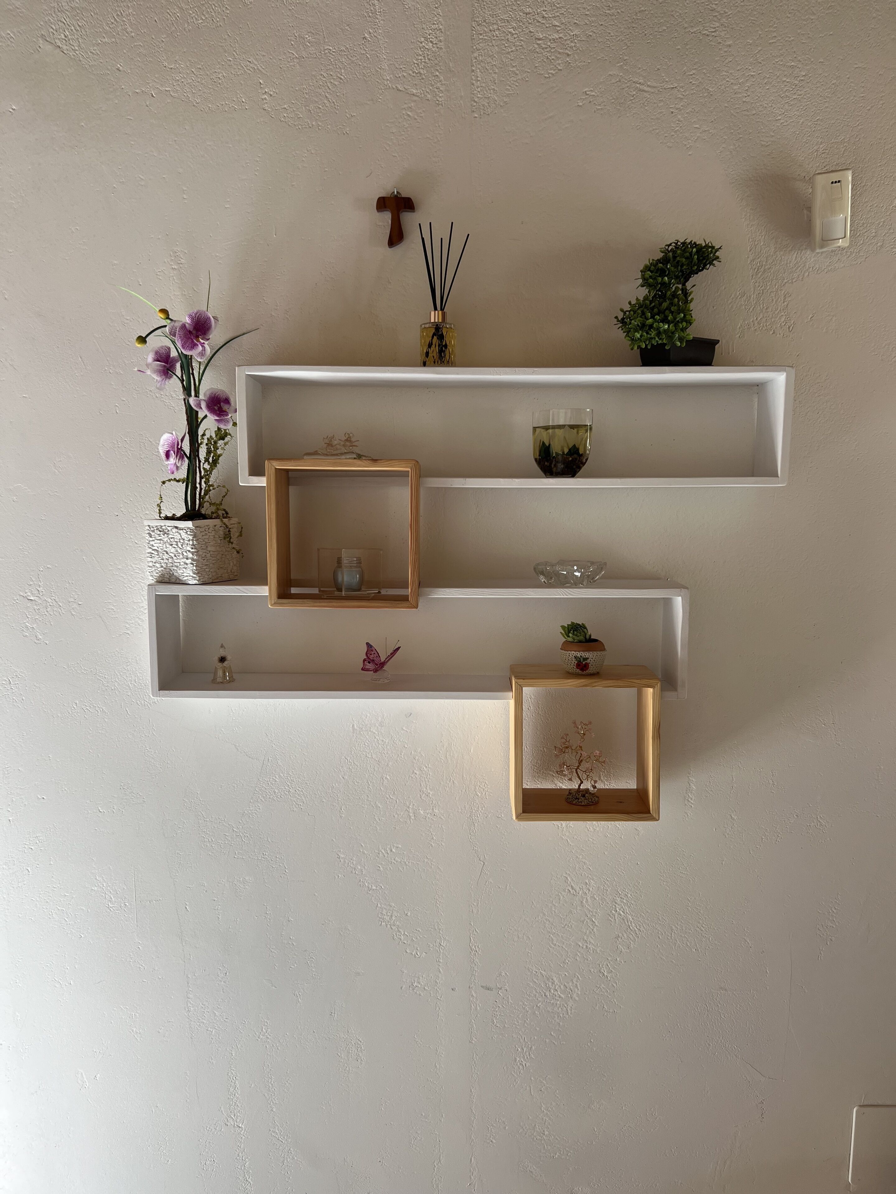Una mensola a parete con tre ripiani, ognuno dei quali contiene diversi oggetti decorativi.