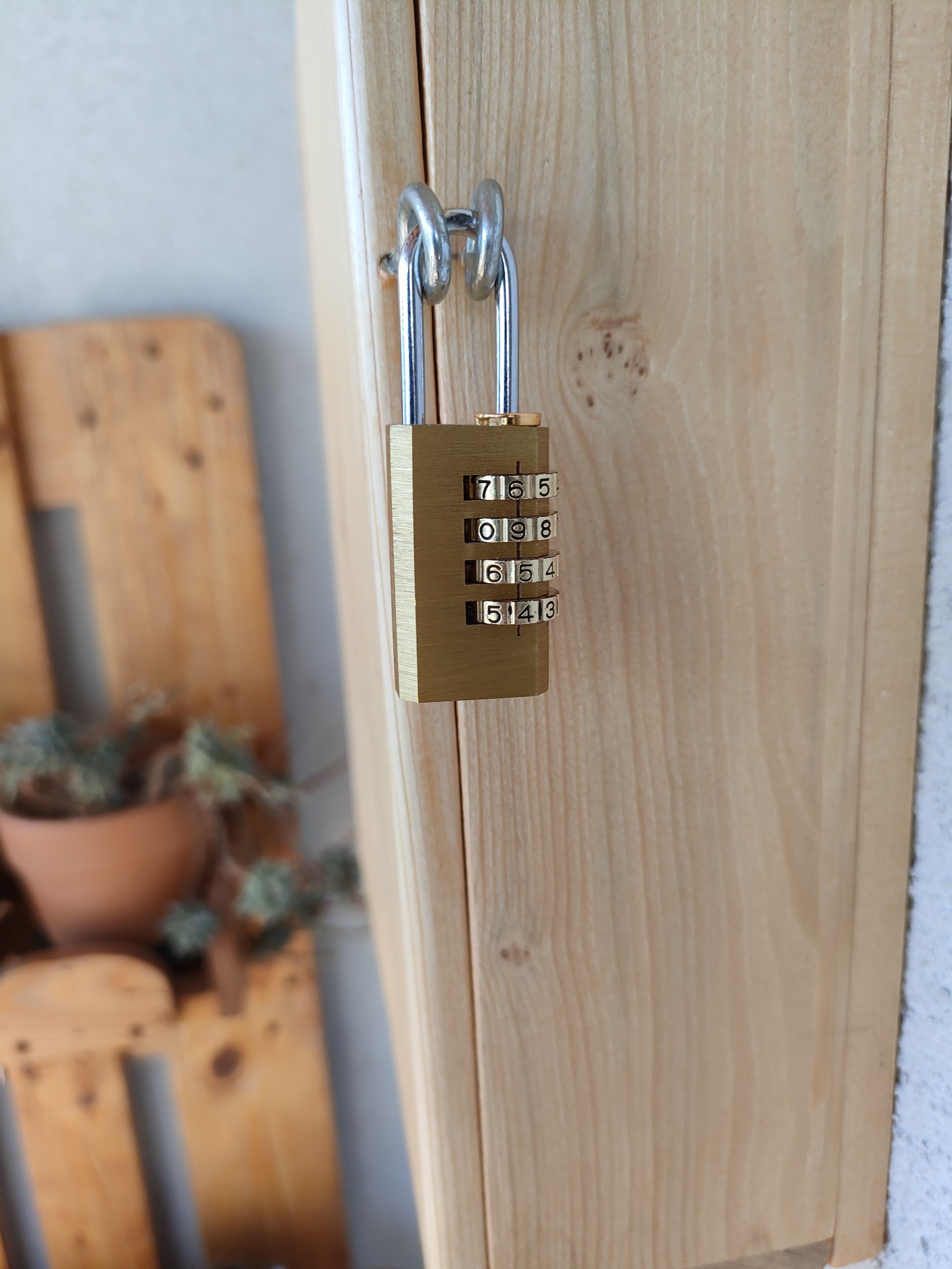 Een messing hangslot met cijfercombinatie op een houten deur.