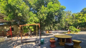 A playground with a swing set, a round table, and stools. - Dev Farm Sasan Gir (Talala)