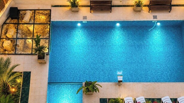 A large indoor swimming pool with clear water, surrounded by stone walls and potted plants.