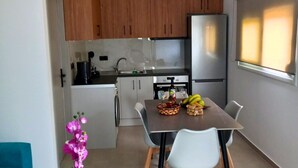 Una cocina moderna con armarios de madera, un refrigerador de acero inoxidable y un comedor con mesa y sillas.