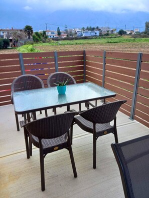 Eine Terrasse mit Glastisch und Korbstühlen mit Blick auf eine Wohngegend mit Häusern und Grünflächen.