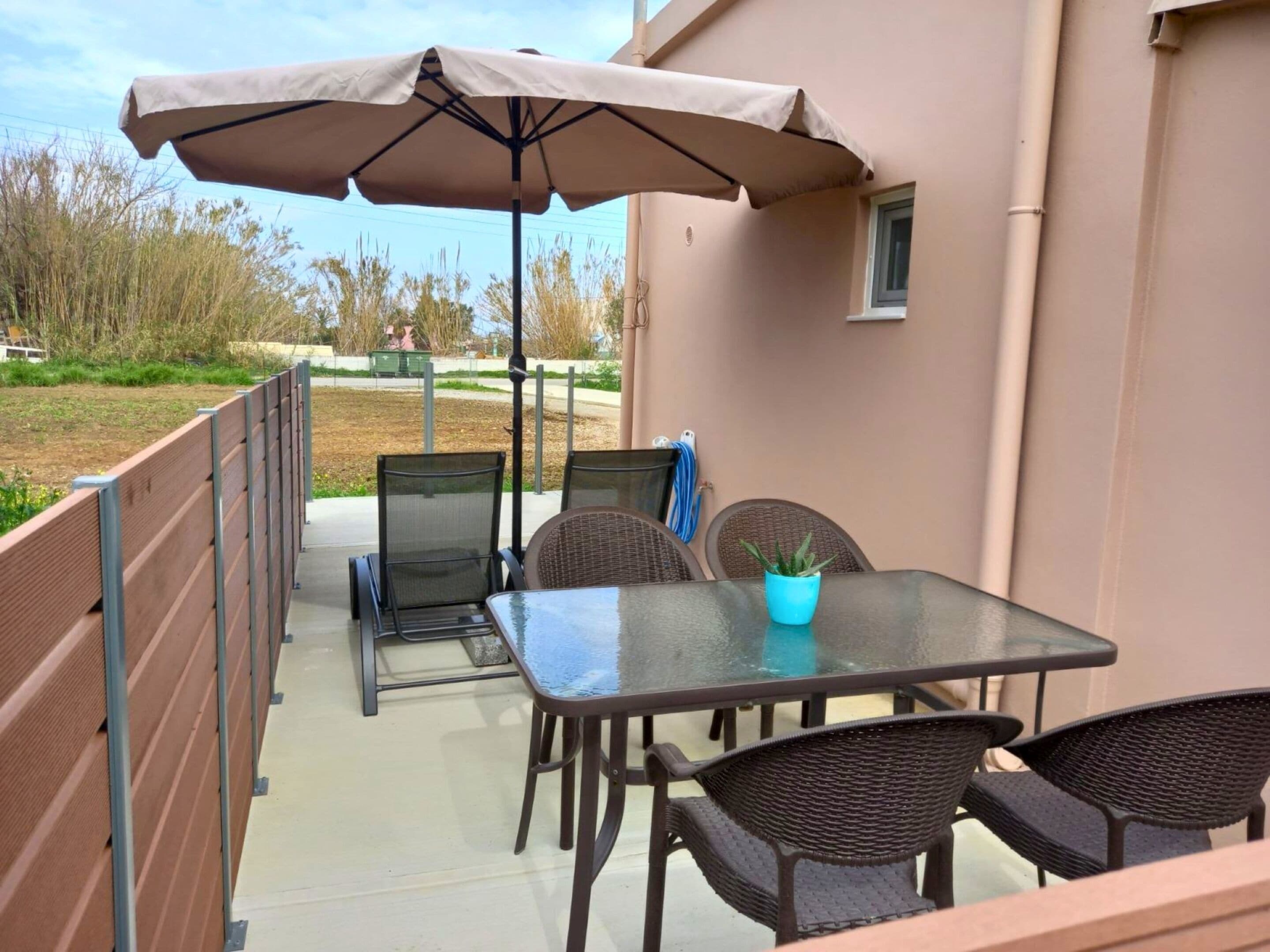 Un patio al aire libre con una mesa, sillas y una sombrilla grande.