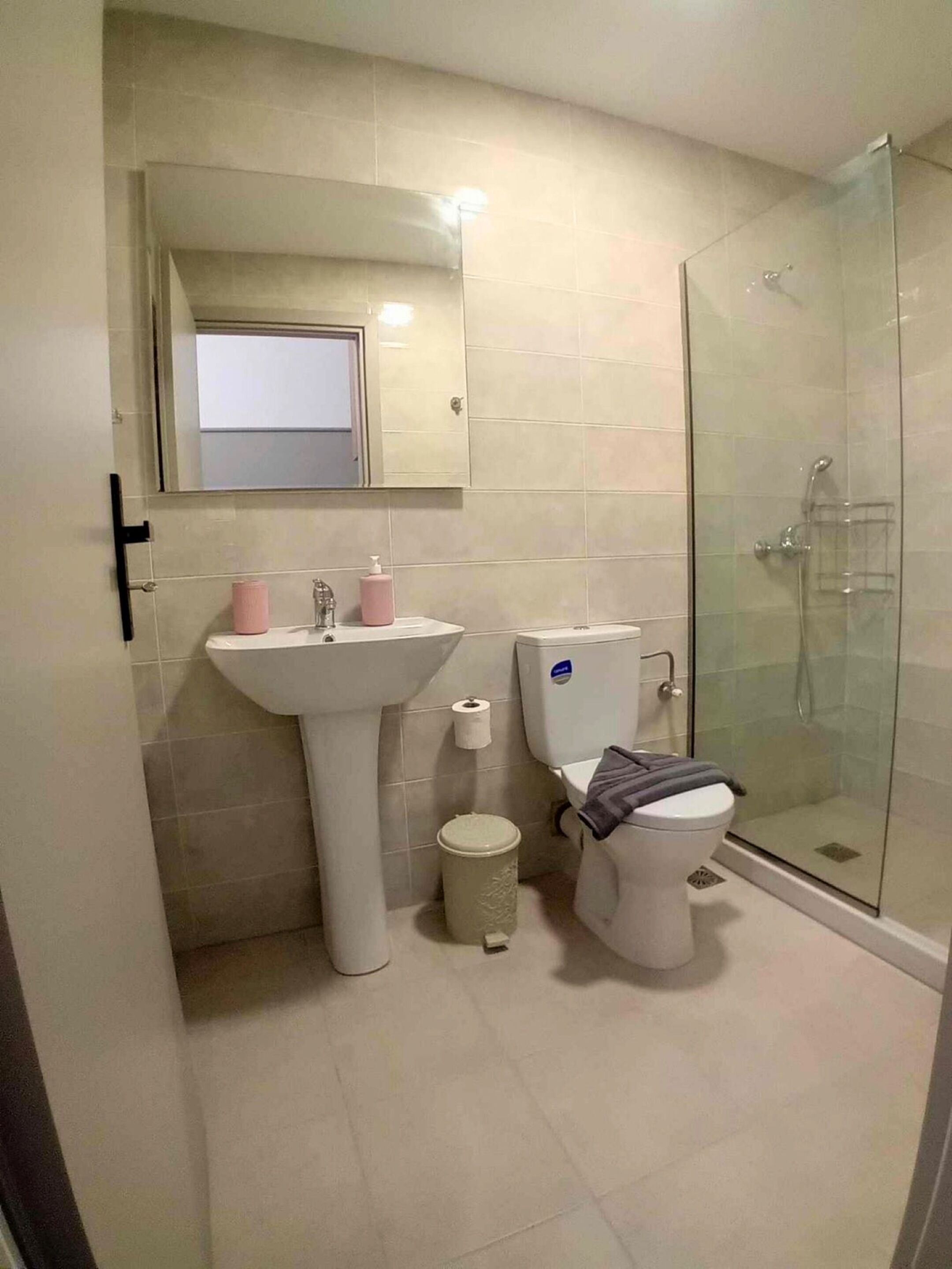 Un baño con lavamanos, inodoro y ducha con mampara de vidrio.