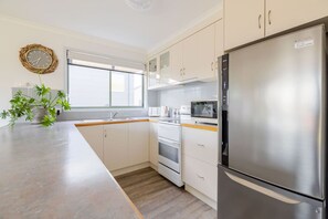 Eine moderne Küche mit einem Edelstahl-Kühlschrank, eingebautem Backofen, Mikrowelle und einem großen Fenster für natürliches Licht.
