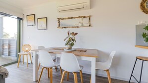 A modern dining area with a wooden table, white chairs, and a potted plant.