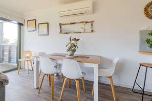 Un comedor moderno con una mesa de madera, sillas blancas y una planta en maceta.