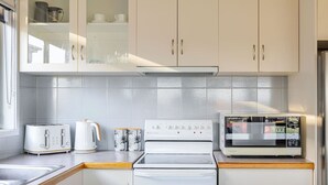 A kitchen with white cabinets, a microwave, a toaster, and a kettle.