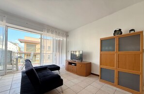 A modern living room with a sofa, TV, and wooden cabinet. - Family-Friendly Apartment Near Beach and Tourist Hub, Salou (Salou)
