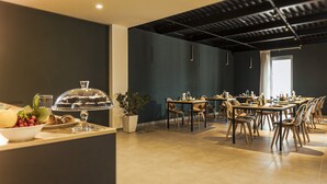 Un comedor moderno con una mesa larga y sillas, un bufé con cubierta de vidrio y una planta en maceta.