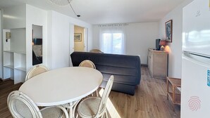 A compact living space with a dining area, sofa, and kitchenette.