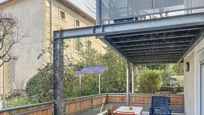 An outdoor seating area with a table and chairs, a covered patio, and a sign indicating a nearby location.