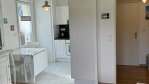 Une cuisine moderne avec des meubles blancs, un coin repas doté d’une table et de chaises blanches, et un plancher en bois.