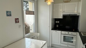 Une cuisine de taille réduite avec des meubles blancs, un plan de travail noir et une table blanche.