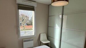 Ein Schlafzimmer mit Bett, Fenster, Stuhl und Heizkörper.