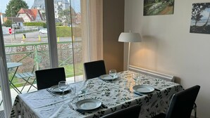 Ein Essbereich mit einem Tisch für vier Personen, einer Lampe und Blick auf eine Wohnstraße.