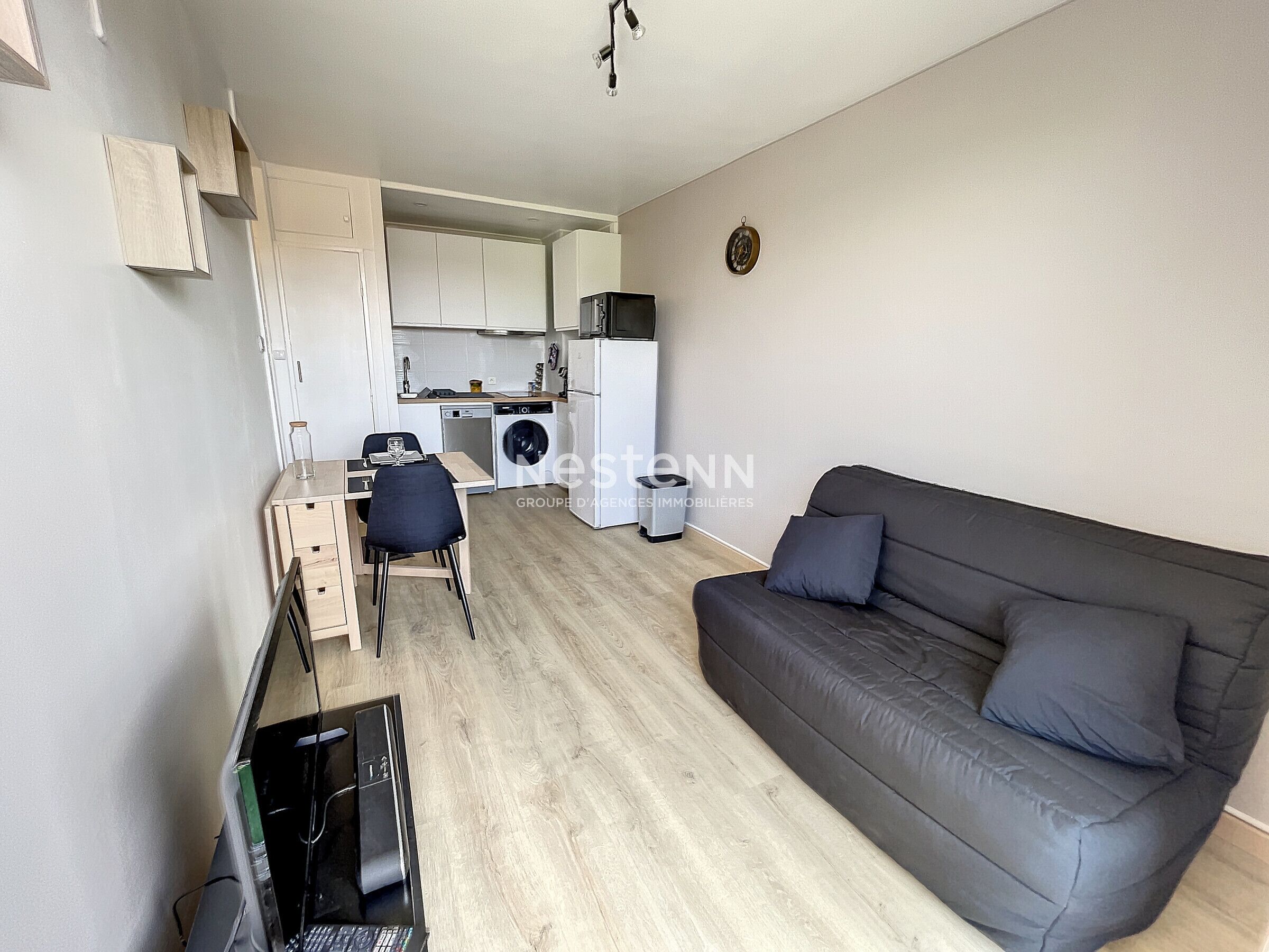 A compact living space with a sofa, a dining area, a kitchen, and a washing machine.