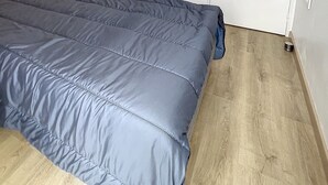 A bedroom with a large bed, a wooden nightstand, and a wooden floor. - 1-Bedroom Apartment 100m from Beach - Sleeps 4, Air Conditioning, Nearby Parking (Argelès-sur-Mer)