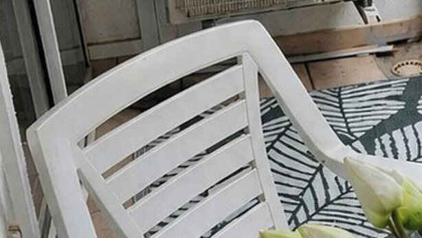 A room with a white chair, a potted plant, and a Mitsubishi air conditioner. - Cozy T2 Apartment with Terrace, 400m from the Beach (Argelès-sur-Mer)