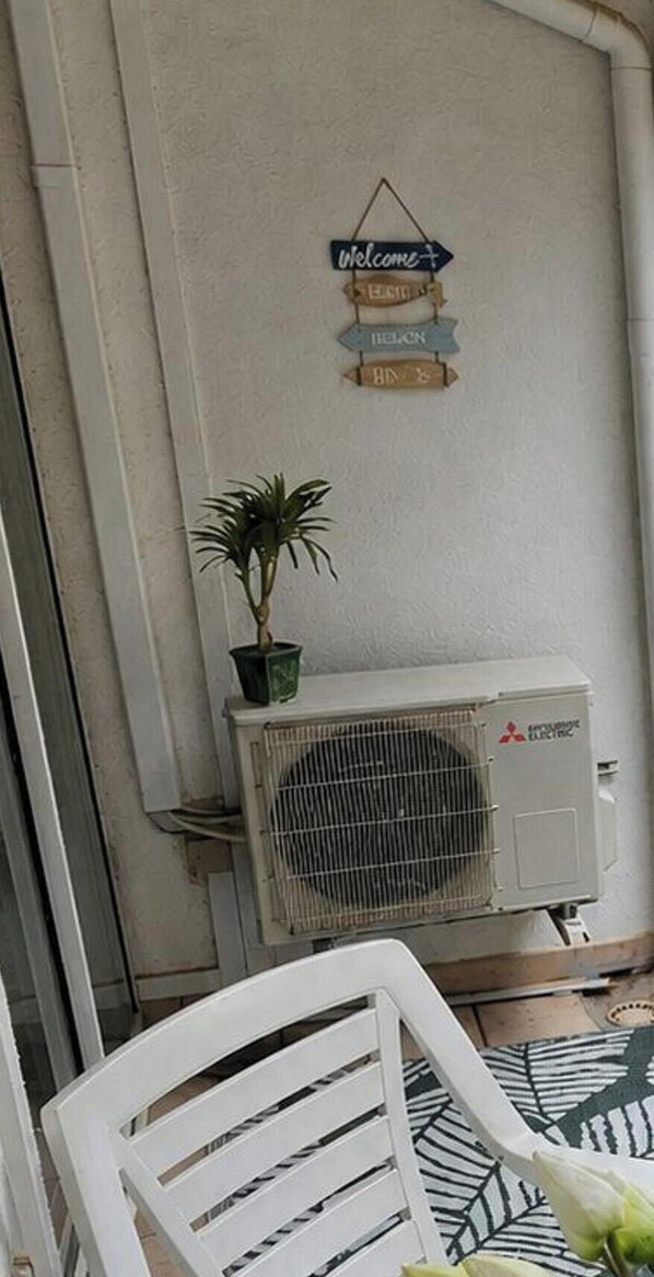 Ein Zimmer mit einem weißen Stuhl, einer Topfpflanze und einer Mitsubishi-Klimaanlage.