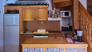 A compact kitchen with wooden cabinets, a built-in microwave, and a coffee maker.
