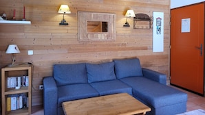 A cozy room with a blue sofa, a wooden coffee table, and two wall-mounted lamps.