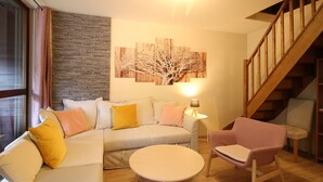 A modern living room with a sofa, armchair, and round coffee table. A staircase is visible in the background. - Duplex in Mont-Dore with parking, near center and slopes (Mont-Dore)