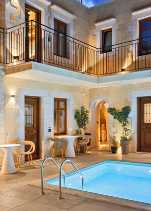 A two-story building with a swimming pool, outdoor seating, and potted plants. - Mansio Boutique Hotel (Rethymno)