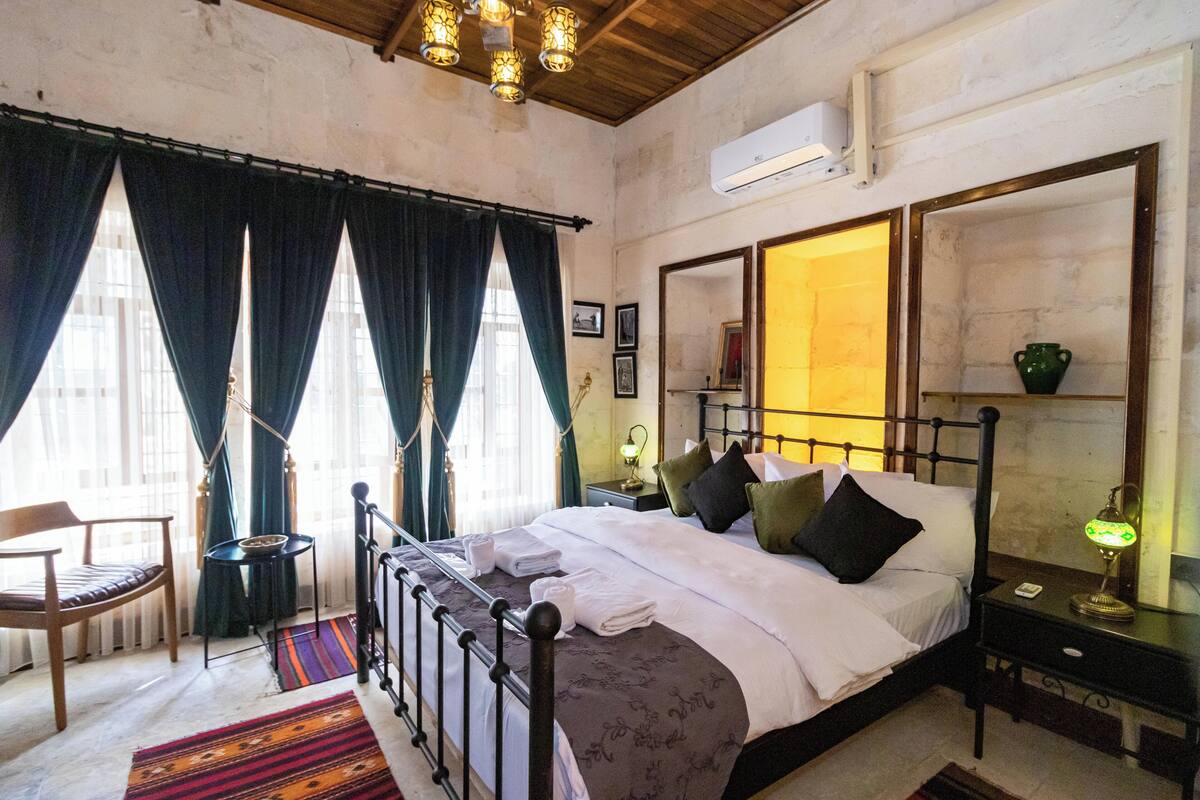 A bedroom with a bed, a chair, a nightstand, and a window with curtains.