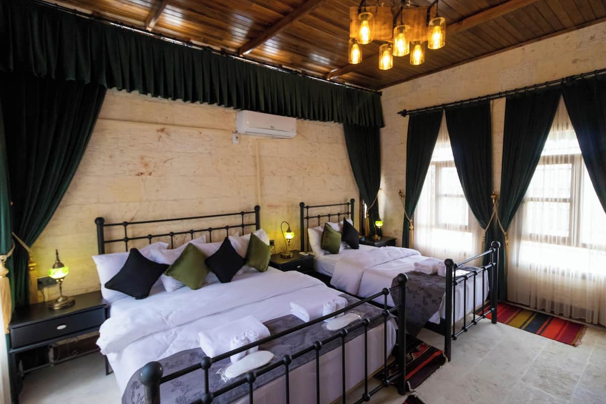 A double room with two beds, a wooden ceiling, and a large window with curtains.