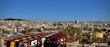 A rooftop terrace with a wooden pergola and colorful fabric drapes.