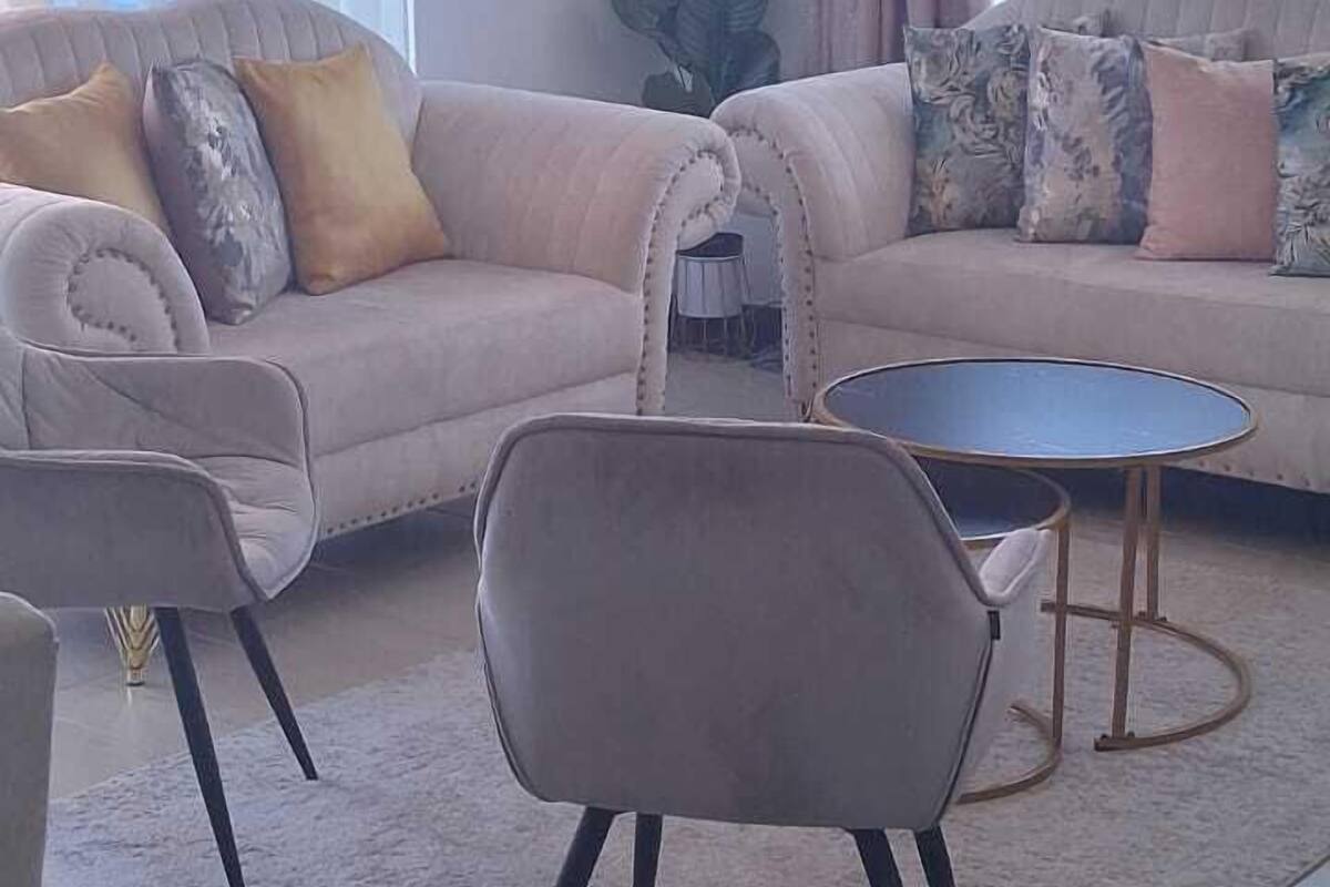 Una sala de estar con un sofá, dos sillones, una mesa de centro y un ventilador de techo.