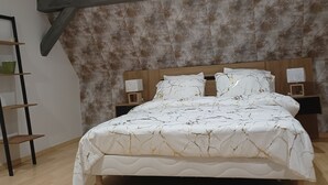 A bedroom with a wooden bed, a slanted ceiling, and a patterned wall. - Gîte "chez L'oncle Paul" (Urschenheim)