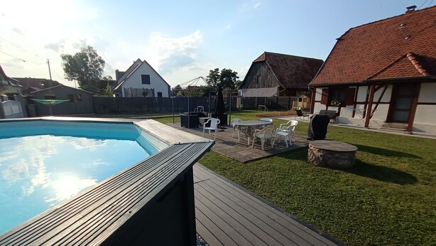 A backyard with a swimming pool, wooden deck, and outdoor furniture. - Gîte "chez L'oncle Paul" (Urschenheim)