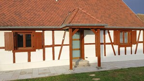 A traditional half-timbered house with a sloped red-tiled roof, a wooden door, and a small porch. - Gîte "chez L'oncle Paul" (Urschenheim)