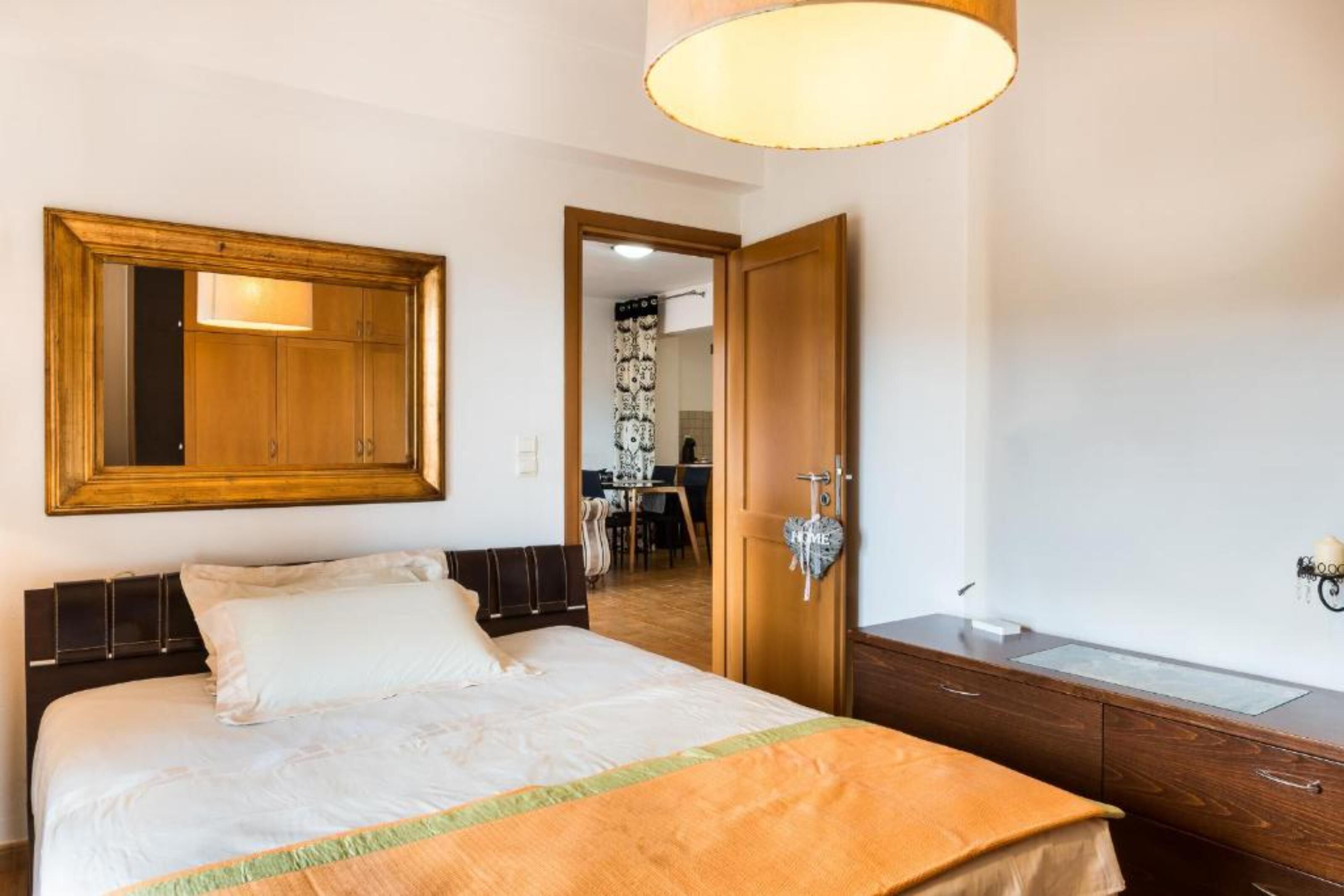 Een hotelkamer met een groot bed, een houten garderobe, een spiegel en een bureau met lamp.