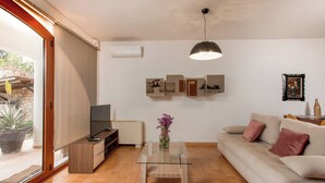 A modern living room with a glass coffee table, beige sofa, and a TV on a wooden stand. - Zen Serenity Retreat (Chania)