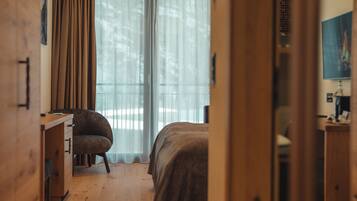 Una habitación con cama, escritorio y silla. Hay una ventana con cortinas.