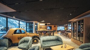 A modern interior with a vintage car, seating, and a bar area. - Hotel Porta Cervino - Parking & Dining (Taesch)