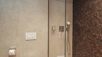 Un baño moderno con cabina de ducha de vidrio, un inodoro y un revestimiento de azulejos.