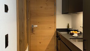 A modern kitchen with wooden flooring, a built-in oven, and dark cabinetry. - Hotel Porta Cervino - Parking & Dining (Taesch)