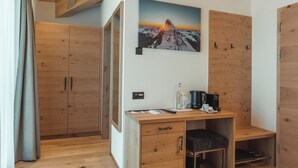 A room with wooden flooring, a desk with a chair, a bed, and a wardrobe. - Hotel Porta Cervino - Parking & Dining (Taesch)