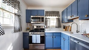 A kitchen with blue cabinets, a stainless steel stove, and a dishwasher. - Birdhaus (Atlanta)
