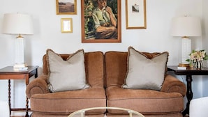 A brown sofa with checkered pillows, a framed painting, and two lamps on either side.