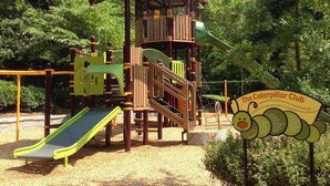 A playground with a slide, climbing structures, and a sign reading "The Caterpillar Club". - Birdhaus (Atlanta)