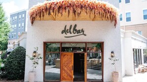 A building with a wooden door and the word "delbar" on the facade. - Birdhaus (Atlanta)